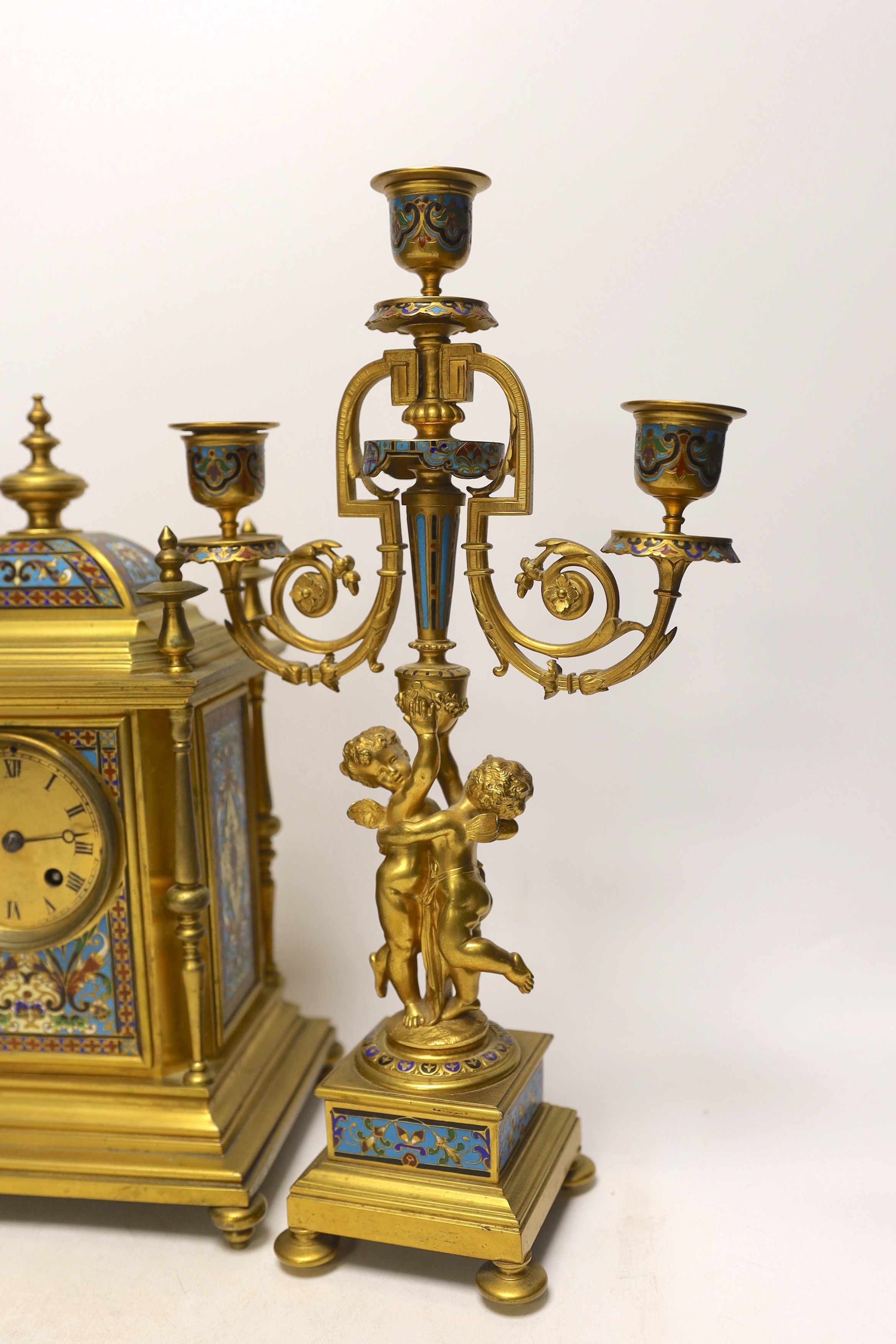 A late 19th/early 20th century French champleve and gilt metal clock garniture, 37cm
